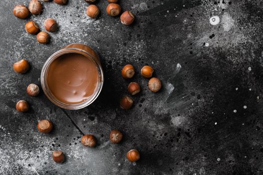 Chocolate hazelnut in jar with nuts, on black dark stone table background, top view flat lay, with copy space for text