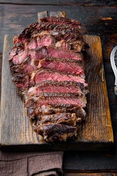 Fresh grilled meat. Grilled beef steak medium rare black angus rib eye steak, on wooden serving board, on old dark wooden table background