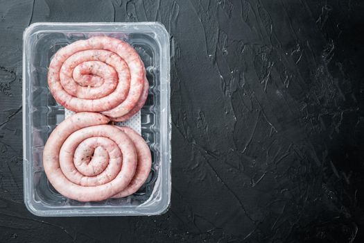 Raw snail sausage in traditional spiral, on black background, in plastic pack, top view flat lay , with space for text copyspace