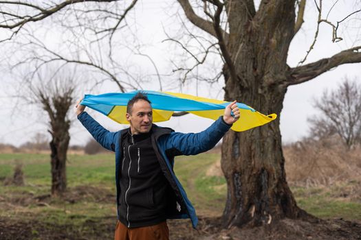 man with the flag of Ukraine near the burnt tree