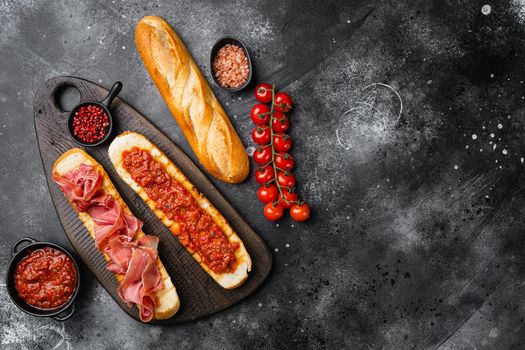 Crusty toast with fresh tomatoes and cured ham set, on black dark stone table background, top view flat lay, with copy space for text
