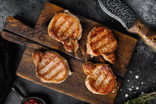 Grilled pork steak tenderloin meat set, on black dark stone table background, top view flat lay