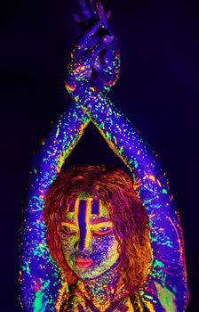 Neon goddess. Cropped shot of a young woman posing with neon paint on her face.