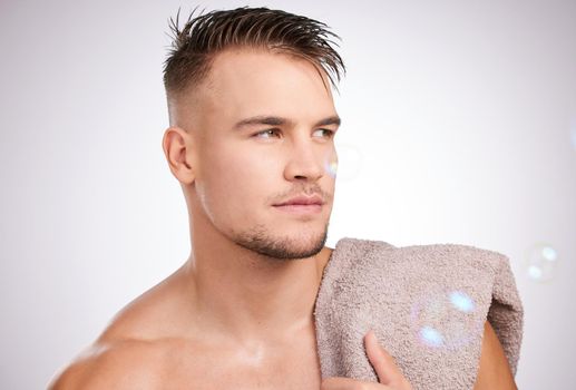 Looking good from every angle. Shot of a young man holding a towel against a grey background.