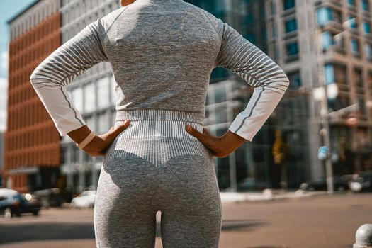 Back view of sportswoman in active wear standing on the street