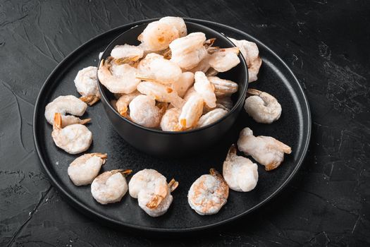 Boiled and frozen shrimps, in bowl, on black stone background