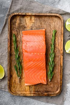 Fresh salmon steak, with herbs, on gray stone table background, top view flat lay
