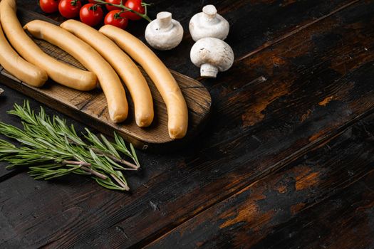 Classic boiled meat sausages, on old dark wooden table background, with copy space for text