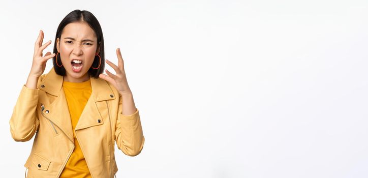 Asian angry woman arguing, shaking hands angry and screaming, shouting with frustrated face, standing over white background