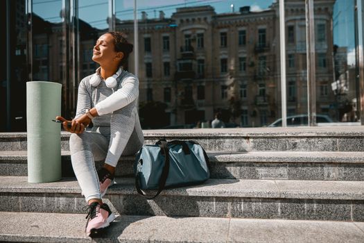 Sportswoman in active wear resting in urban setting. People and sport concept