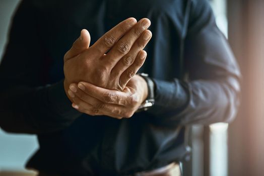 Feeling numbness and pain in his hands. Closeup shot of an unidentifiable businessman suffering with pain in his hands.