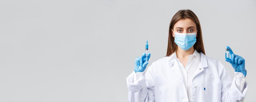 Covid-19, preventing virus, healthcare workers and quarantine concept. Doctor in personal protective equipment, medical mask and scrubs making coronavirus vaccine shot, hold syringe and ampoule