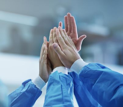 Cooperation for a successful operation. Cropped shot of a team of surgeons giving each other a high five.