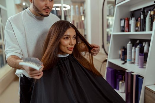 Woman looking at herself in mirror, pleased with a hairstyle at beauty salon