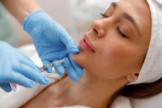 Closeup of young woman receiving hyaluronic acid injection in beauty salon