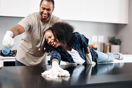 The dirt busting father daughter duo. Shot of a young girl helping her father clean the kitchen counter at home.