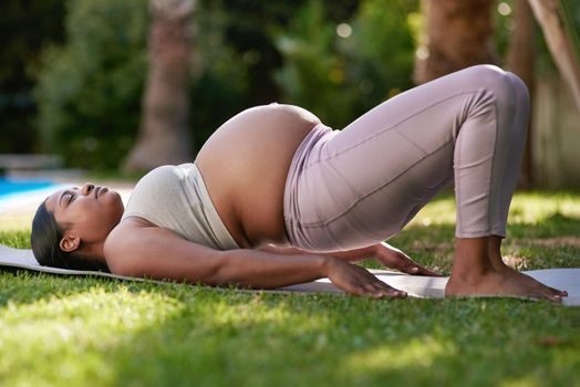 Low-impact exercises are great for women in their third trimester. Shot of a pregnant woman doing yoga outside.