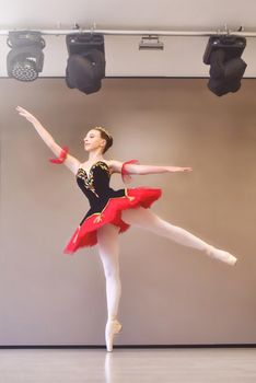 A young ballerina stands gracefully in pointe shoes on her toes in the studio.Ballet student practicing classical dance in studio before performance.