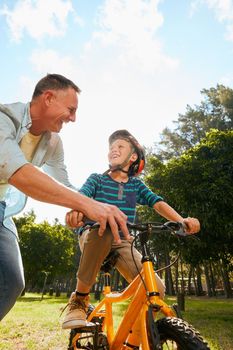 Dads got you. Shot of a father teaching his son how to ride a bicycle.