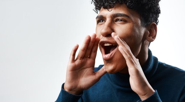 News travels faster by word of mouth than mail. Studio shot of a young man yelling against a grey background.