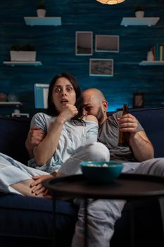 Couple watching scary horror movie on television channel