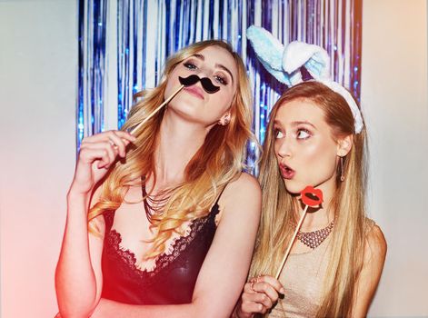 Were the life of the party. Shot of two beautiful young women having fun with props in a photobooth.