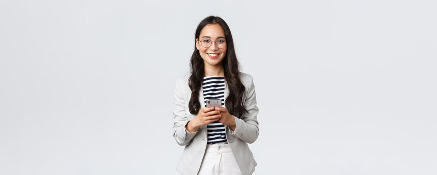Business, finance and employment, female successful entrepreneurs concept. Smiling pleasant asian businesswoman, real estate broker wear glasses, using mobile phone to contact clients
