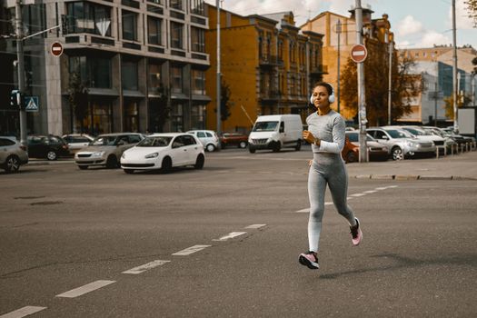 Sportswoman in light gray active wear running outdoors in the daytime