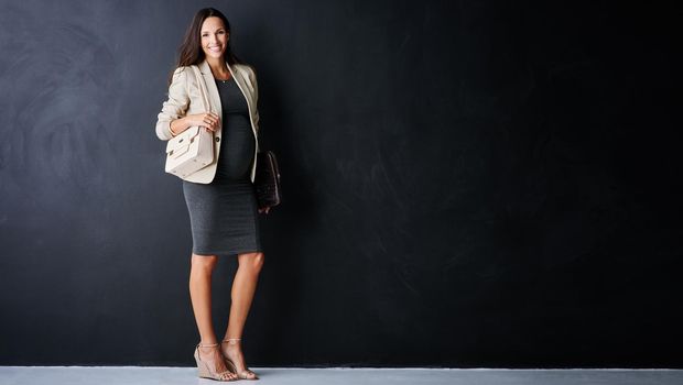 Pregnancy suits her. Studio portrait of a young pregnant businesswoman standing against a black background.