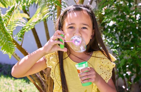 My bubbles brings all the fun to the yard. Shot of an adorable little girl blowing bubbles outside.