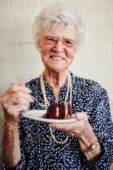 Retirement suits me. Shot of a senior woman eating a slice of cake inside.