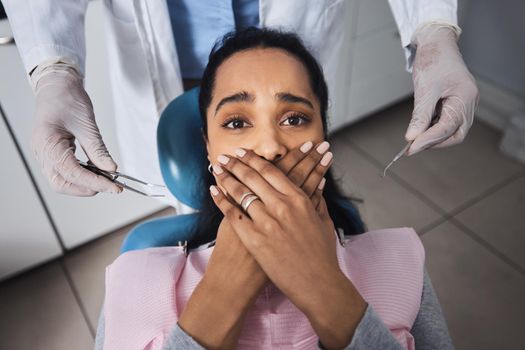 Its business as usual until they bring the tools out. Shot of a young woman looking scared while having dental work done on her teeth.