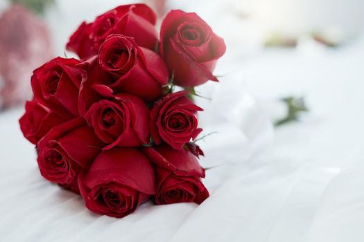 Roses are red and love is forever. Shot of a bunch of red roses lying on a bed.