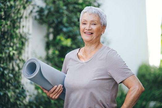 Fitness is a lifestyle. Portrait of an older woman holding an exercise mat before her workout outside.