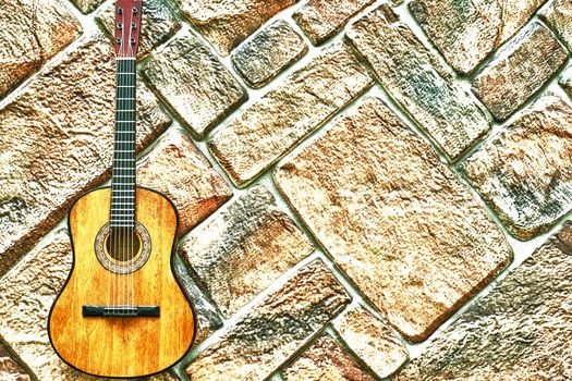 Acoustic yellow guitar on paving gold background.Copy space.