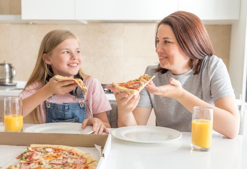 Mother and daughter eating delivered pizza in the kitchen