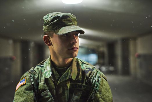 Stay alert, stay alive. Shot of a young soldier standing outside on a cold night at a military academy.