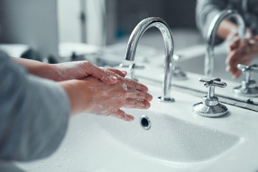 Its vital to practice good personal hygiene. Closeup shot of an unrecognizable woman washing her hands in the bathroom at home.