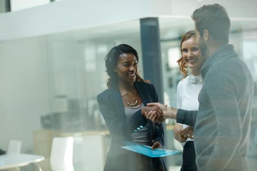 Welcoming a new member to the team. Cropped shot of businesspeople shaking hands in an office.