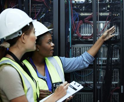 What do you see. Cropped shot of two attractive female programmers working in a server room.