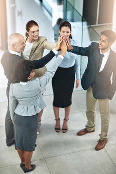 Employee motivation is key in maintaining a pleasant office culture. Shot of a group of businesspeople giving a high-five.