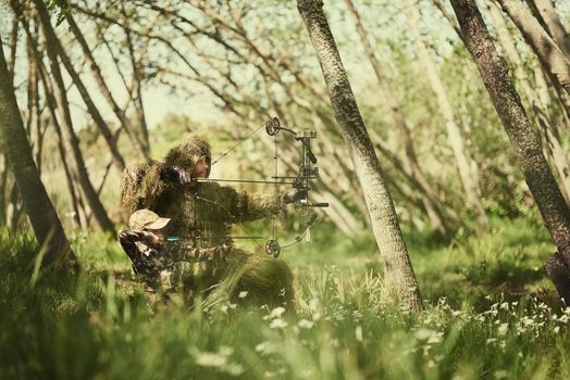 Blending right in to their surroundings. Shot of a father and son in camouflage hunting with bows and arrows in the woods.