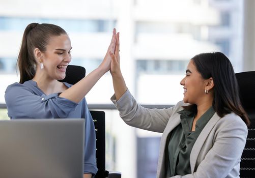 Success can be a team effort too. Shot of two young businesswoman giving each other a high five in an office at work.