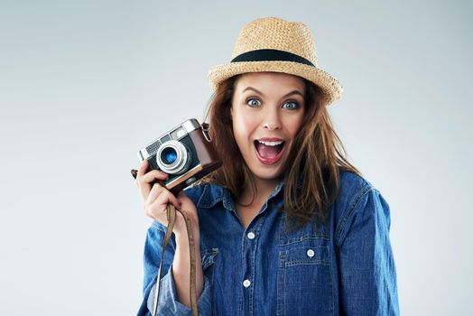 I cant picture a more exciting moment. Studio portrait of a young woman using a vintage camera against a grey background.