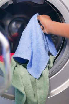 putting towel and cloths in a washing machine.