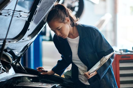 Shell give you the best and least expensive solution for your car problems. Shot of a female mechanic working on a car in an auto repair shop.
