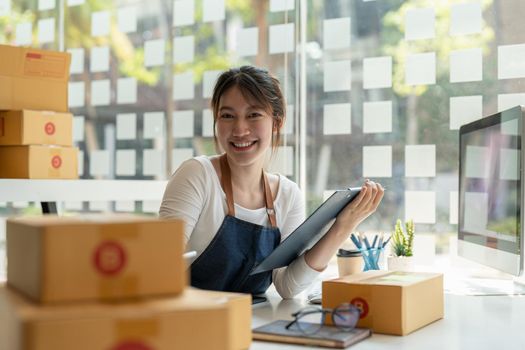 Portrait of Asian young woman SME working with a box at home the workplace.start-up small business owner, small business entrepreneur SME or freelance business online and delivery concept