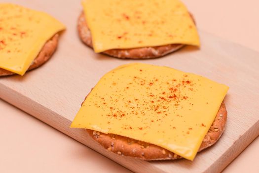 Cracker Sandwiches with Cheese and Paprika on Cutting Board