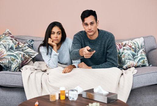 When youre so tuned in you start to tune out. Shot of a young couple watching tv while recovering from an illness at home.