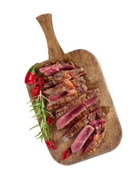 roasted piece of beef ribeye cut into pieces on a vintage brown chopping board, rare doneness. Delicious steak